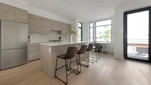 A modern kitchen with a central island, bar stools, and a large window. - Landing | Incredible 2BD in Logan Circle (Washington)