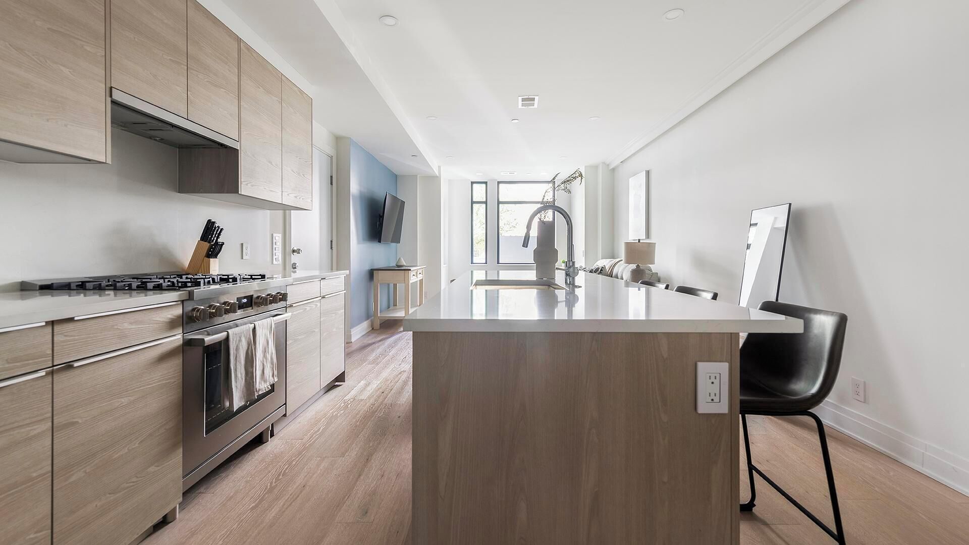 A modern kitchen with wooden cabinets, a central island, and a built-in oven.