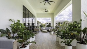 Uma área externa coberta com plantas em vasos, assentos e um ventilador de teto.