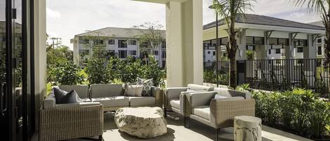 A covered outdoor seating area with wicker furniture and a stone accent piece.