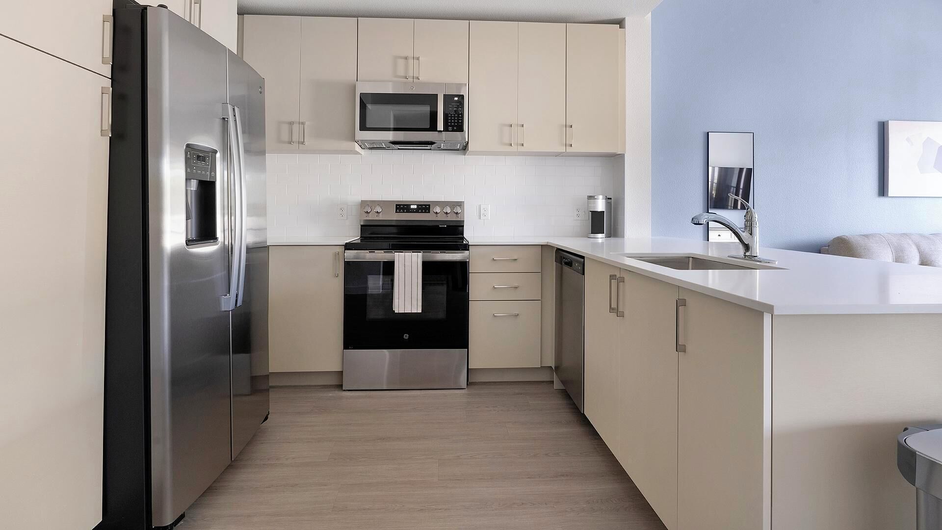 A modern kitchen with stainless steel appliances, a microwave, oven, and a sink.