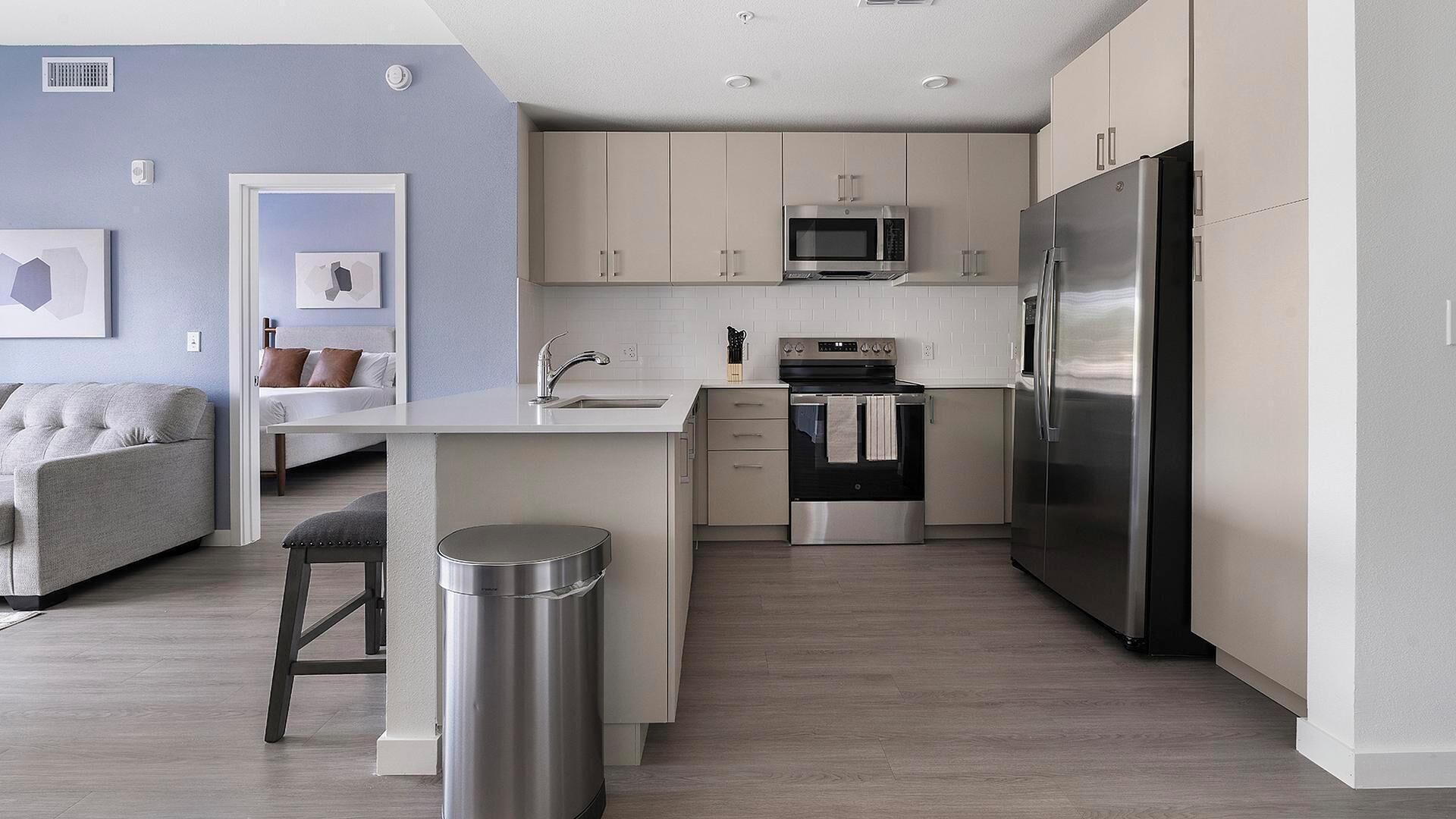 Una cocina moderna con una isla central, electrodomésticos de acero inoxidable y armarios de colores claros.