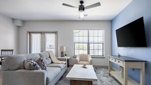 Una sala de estar con sofá, mesa de centro, televisor y escritorio.
