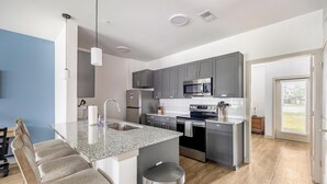 Eine moderne Küche mit Granit Arbeitsplatten, Edelstahlgeräten und einer Kochinsel mit Barhocker.
