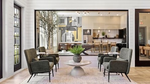 Un interior moderno con una zona de estar que incluye cuatro sillones y una mesa central con un florero.
