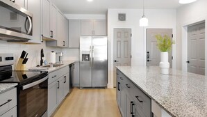 Una cocina moderna con electrodomésticos de acero inoxidable, encimeras de granito y un diseño minimalista.