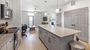 Una cocina moderna con encimeras de granito, horno empotrado y comedor con mesa y sillas.