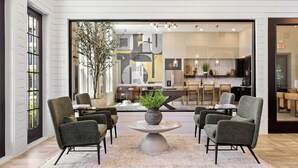 Un interior moderno con una zona de estar que incluye cuatro sillones y una mesa central con un florero.