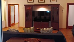 Un salon avec un canapé, un téléviseur et un meuble.
