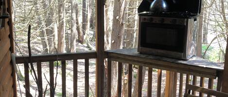 A covered outdoor area with a grill, a cooler, and a table.