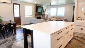 A kitchen with a large island, a dining table, and a seating area with a sofa and chairs.