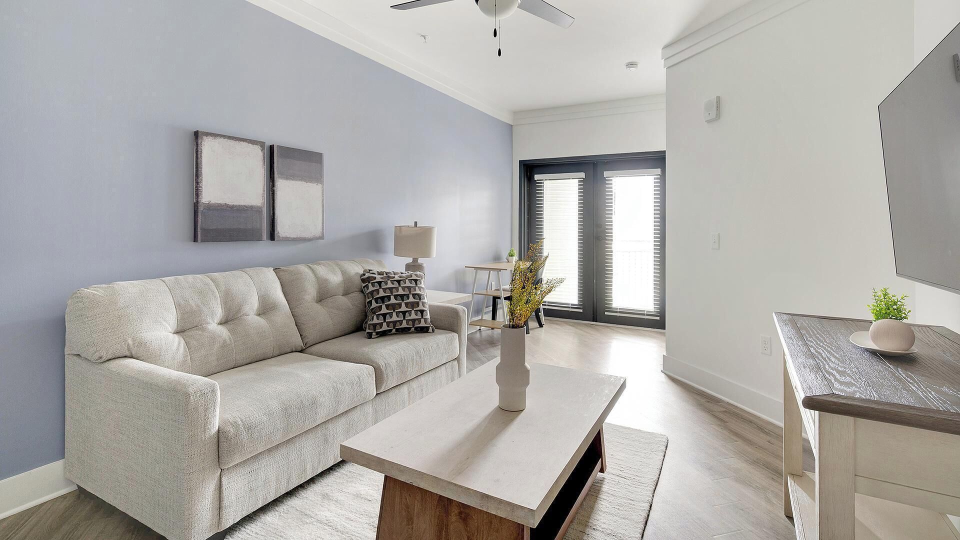 A living room with a sofa, coffee table, lamp, and a small plant on a side table.