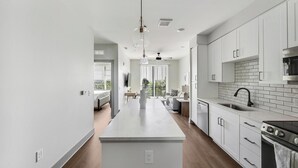 Een moderne keuken met witte kastjes, een centraal eiland en een zwart fornuis.