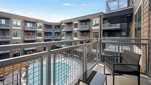 Ein modernes Apartmenthaus mit mehreren Balkonen, einem Schwimmbad und Außenbereichen zum Sitzen.