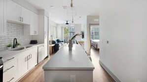 Eine moderne Küche mit weißen Schränken, einer zentralen Kochinsel und einem Essbereich mit Tisch und Stühlen.