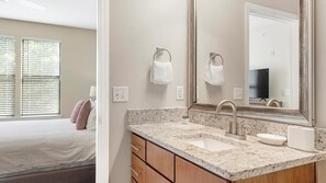 A bathroom with a granite countertop, a sink, a mirror, and two towel rings. - Landing | Spectacular 2BD, Clubhouse, Gym (Charlotte)