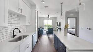 A modern kitchen with white cabinets, a black faucet, and a large island. - Landing | Stylish 1BD, Gym, Courtyard (Nashville)