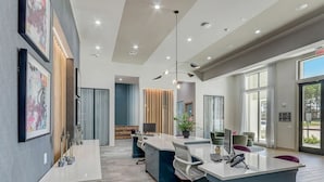 Un espace de bureau moderne doté d’un bureau central, de plusieurs postes de travail et d’une grande fenêtre laissant entrer la lumière naturelle.