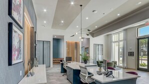 Um espaço de escritório moderno com uma mesa central em ilha, diversas estações de trabalho e uma grande janela que oferece luz natural.