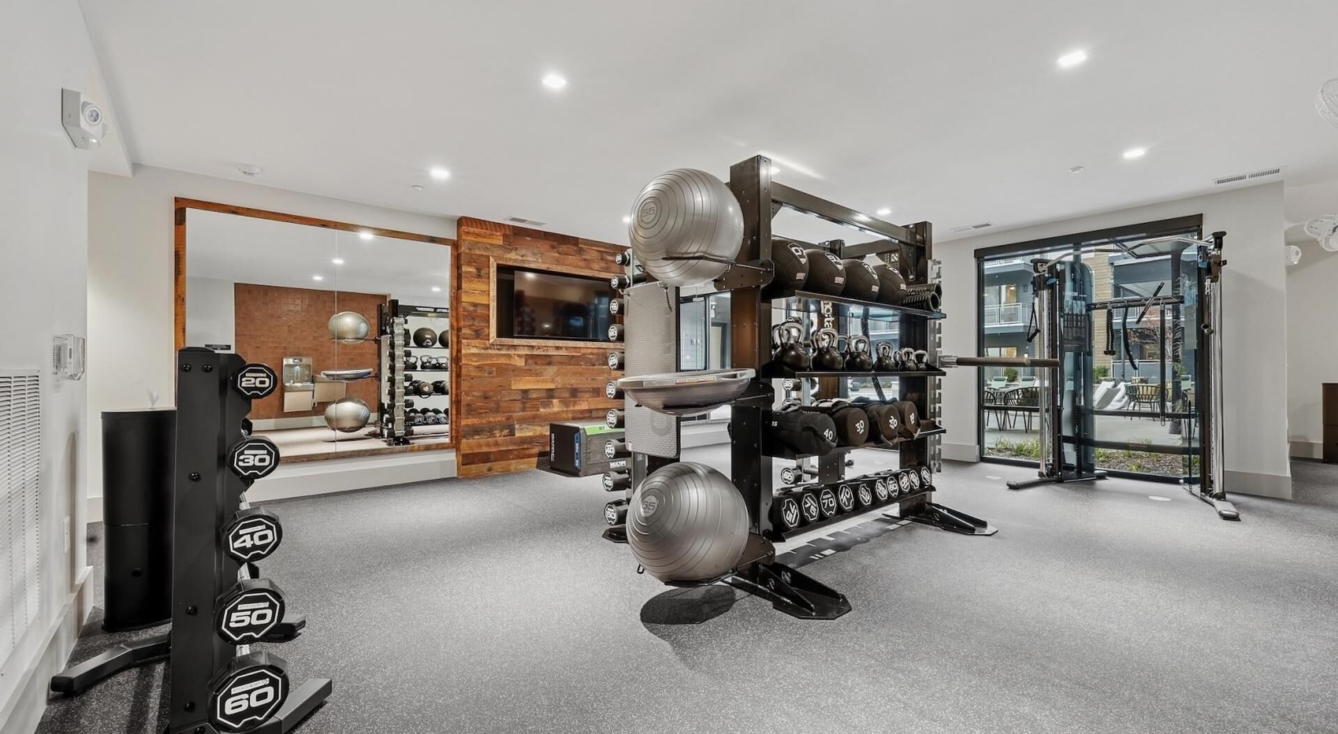 A home gym with weightlifting equipment, a mirror, and a view of the outside.