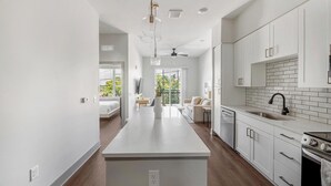 Une cuisine moderne avec des meubles blancs, un îlot central et une vue sur un balcon.