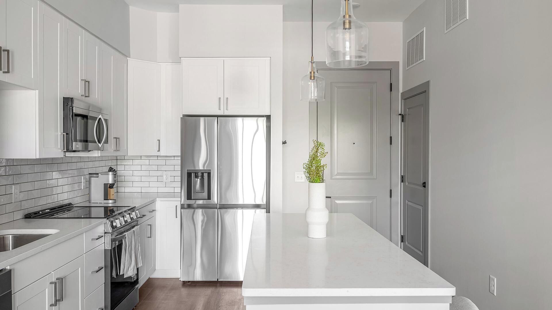 Een moderne keuken met roestvrijstalen apparatuur, witte kasten en een centraal keukenblok.