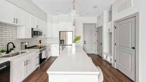 A modern kitchen with white cabinetry, stainless steel appliances, and a central island. - Landing | Chic 1BD, Gym, Yoga Studio (Nashville)