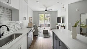 A modern kitchen with white cabinetry, a built-in oven, and a large window with blinds. - Landing | Stunning 1BD, Courtyard, Gym (Nashville)