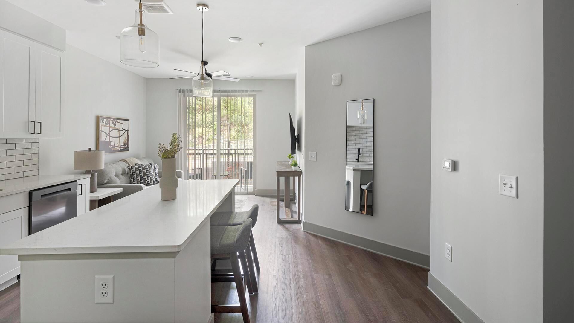 Una cocina moderna con armarios blancos, una isla central y un comedor con vistas al exterior.