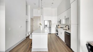 A modern kitchen with white cabinetry, stainless steel appliances, and a central island. - Landing | Spectacular 1BD, Gym, Courtyard (Nashville)