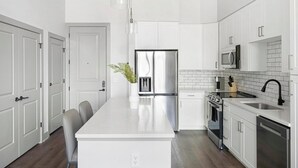 Una cocina moderna con armarios blancos, electrodomésticos de acero inoxidable y una isla central.