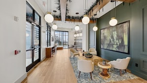 Un interior moderno con una larga mesa de comedor, sillas, luces colgantes y ventanas amplias.