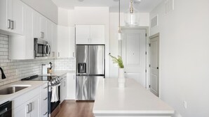 A modern kitchen with white cabinetry, stainless steel appliances, and a central island.