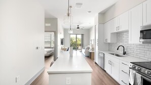 A modern kitchen with white cabinetry, a central island, a microwave, and a dishwasher.