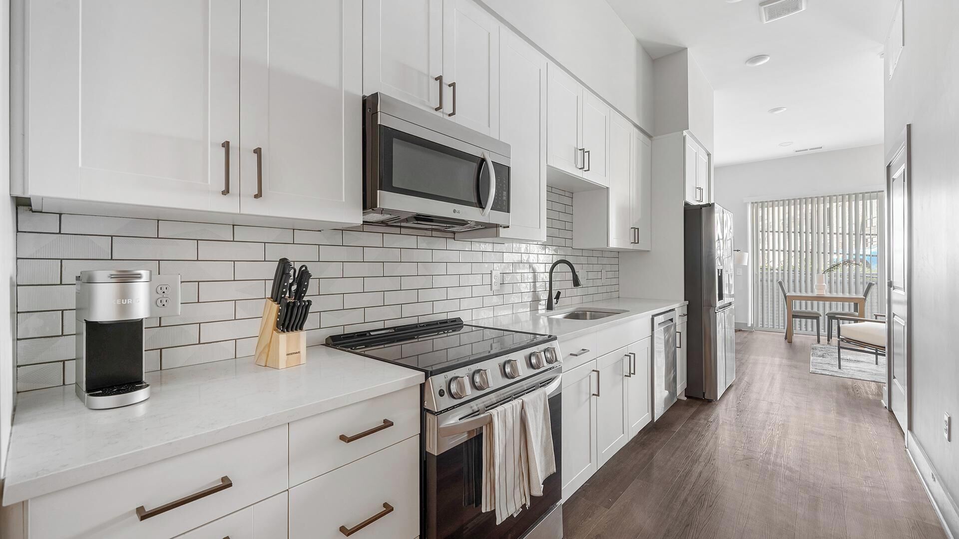 A modern kitchen with white cabinetry, a built-in microwave, a stove, and a refrigerator.