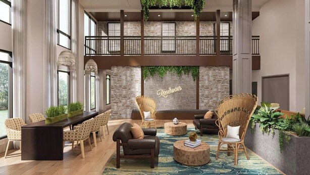 A spacious lobby with a high ceiling, a stone wall, and a seating area with wicker chairs and a sofa. - Landing | Chic 2BD, Courtyard, Gym (Nashville)