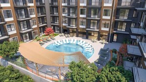 A modern apartment building with a central courtyard featuring a swimming pool, lounge chairs, and outdoor seating. - Landing | Chic 2BD, Courtyard, Gym (Nashville)