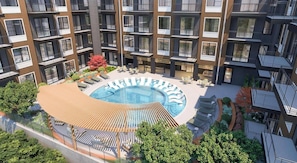 A modern apartment building with a central courtyard featuring a swimming pool, lounge chairs, and outdoor seating. - Landing | Amazing 2BD, Yoga Studio, Gym (Nashville)