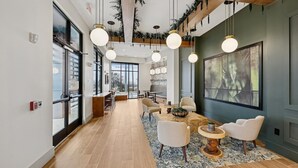 A modern interior with a long dining table, chairs, hanging lights, and large windows. - Landing | Chic 2BD, Courtyard, Gym (Nashville)
