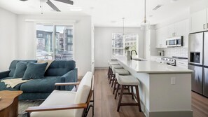 A modern apartment with a living area, kitchen, and a balcony with a city view. - Landing | Spectacular 2BD, Gym, Yoga Studio (Nashville)