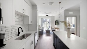A modern kitchen with white cabinets, a black faucet, and a Keurig coffee maker. - Landing | Stylish 1BD, Courtyard, Gym (Nashville)