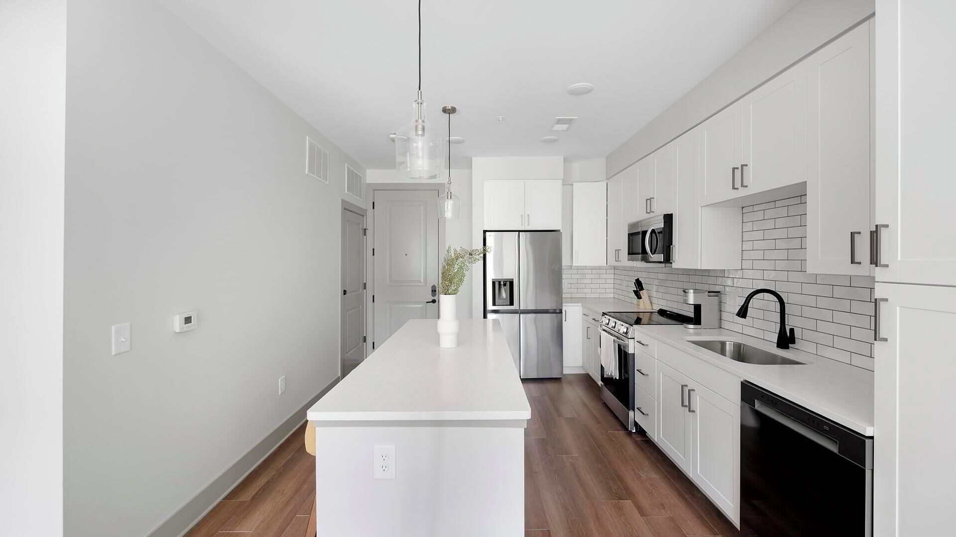 Una cocina moderna con armarios blancos, electrodomésticos de acero inoxidable y una isla central.