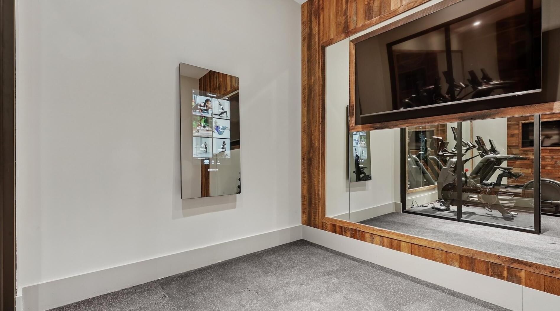 Une salle de sport équipée de matériel d’exercice, dotée d’un grand miroir et d’un mur décoratif en bois.