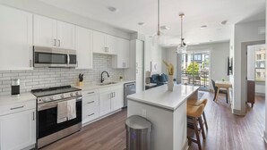 Une cuisine moderne avec des meubles blancs, un four à micro-ondes encastré, une cuisinière et un évier.