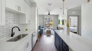 Une cuisine moderne avec des meubles blancs, un robinet noir et un dosseret carrelé.