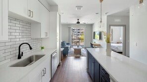 A modern kitchen with white cabinetry, a black faucet, and a tiled backsplash. - Landing | Spectacular 1BD, Yoga Studio, Gym (Nashville)