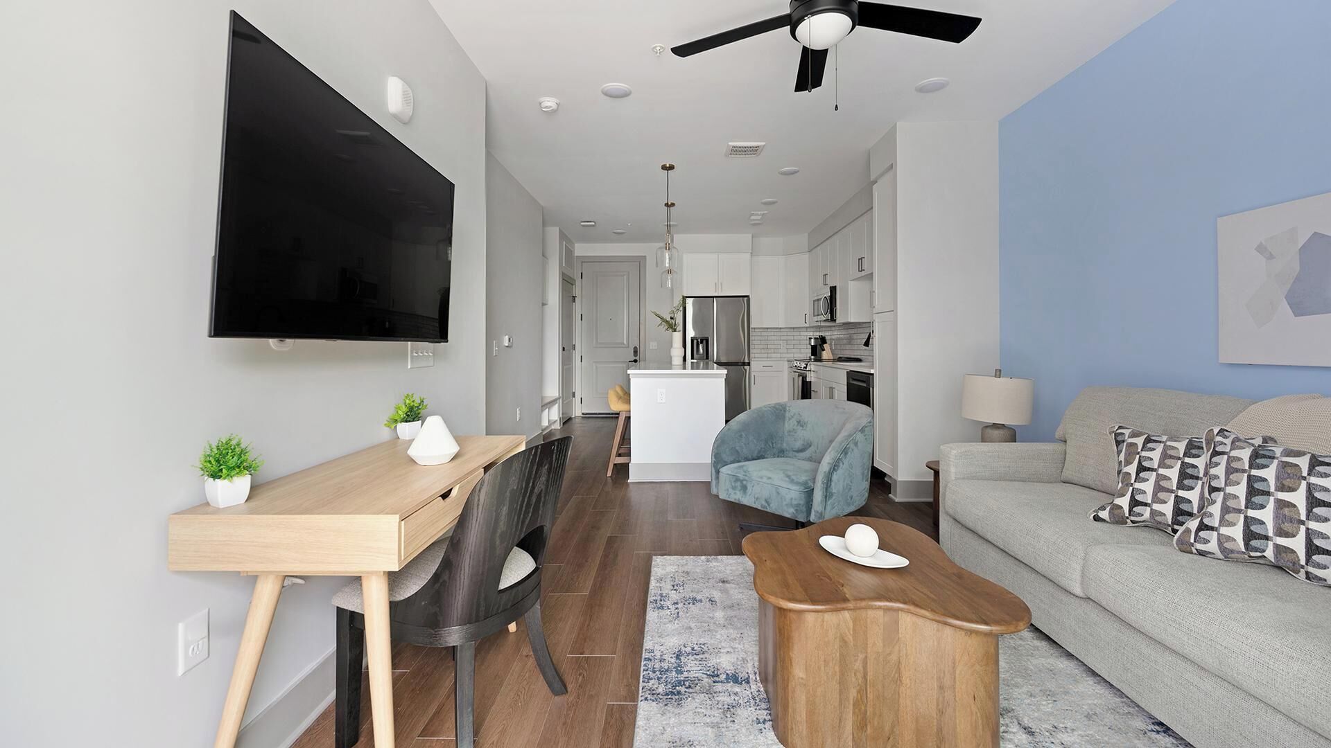Un salon moderne comprenant un téléviseur à écran plat, un canapé, une table basse et un bureau avec une chaise.