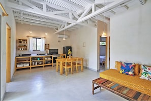 Eine moderne Küche mit Holzmöbeln, einem Essbereich und einem Sofa mit bunten Kissen.