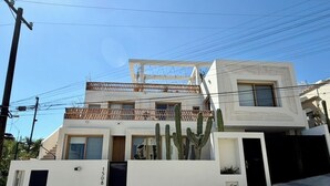 Een modern, tweelaags gebouw met een witte gevel, een balkon en een cactustuin.