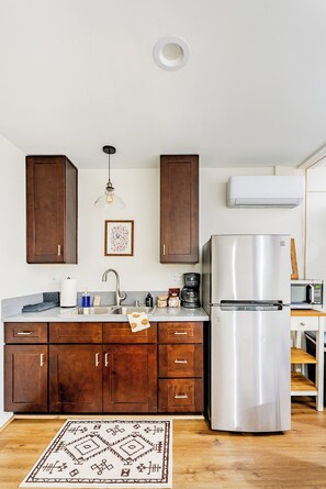A kitchen with wooden cabinets, a stainless steel refrigerator, a microwave, and a coffee maker.